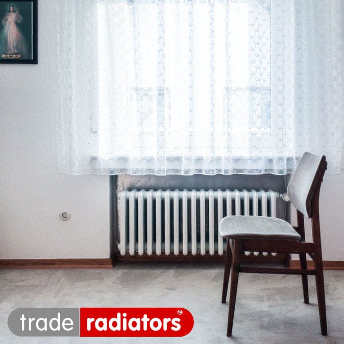 A chair in front of a radiator under a window