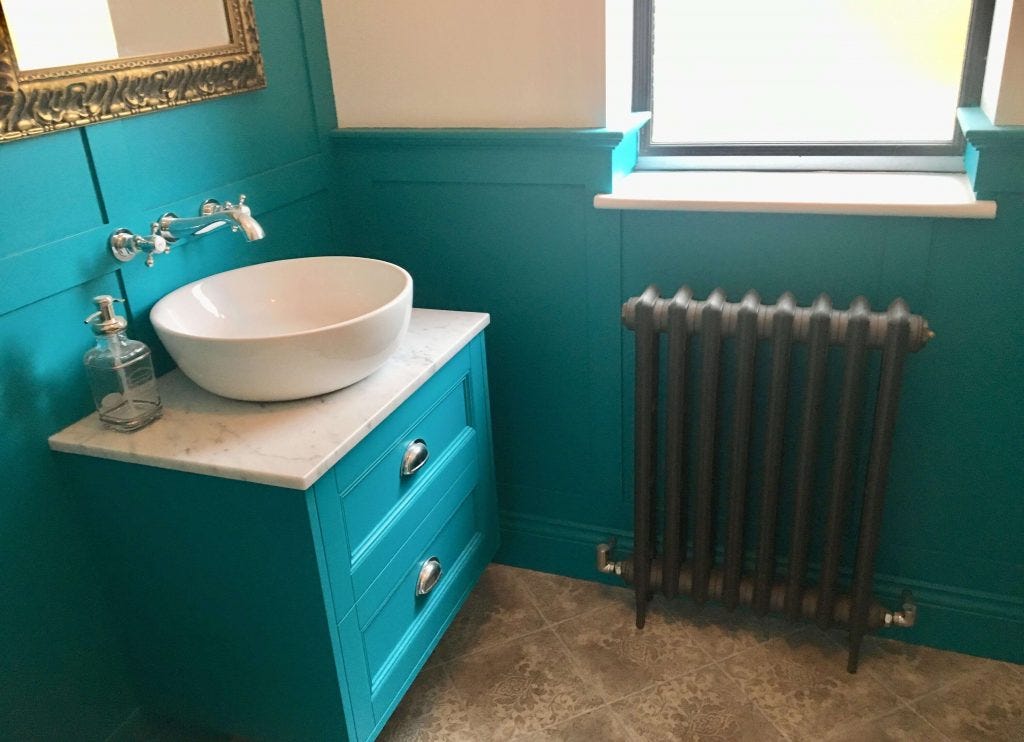 Stylish column radiator in a teal bathroom