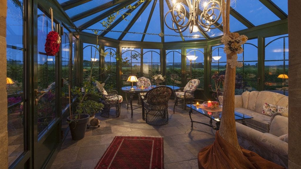 A conservatory with furniture and a view out onto the garden