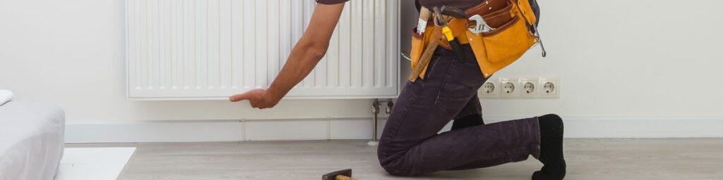 A plumber removing a radiator from the wall