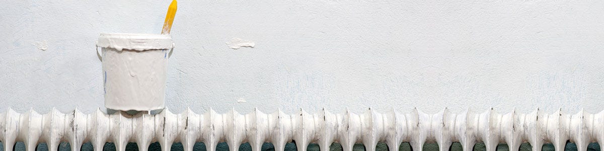 A bucket of paint on top of a radiator