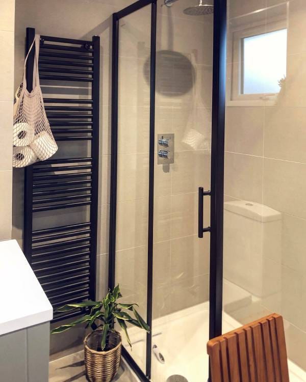A black heated towel rail next to a shower cubicle