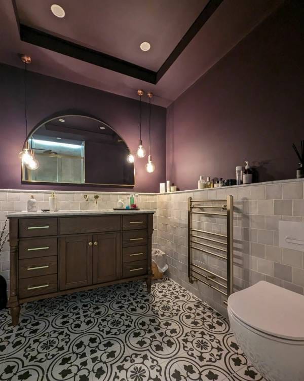A Reina Ottone heated towel rail on the wall in a purple bathroom