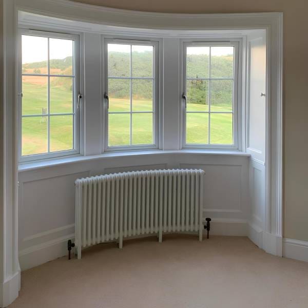 White Nordic Oslo curved column radiator under a bay window