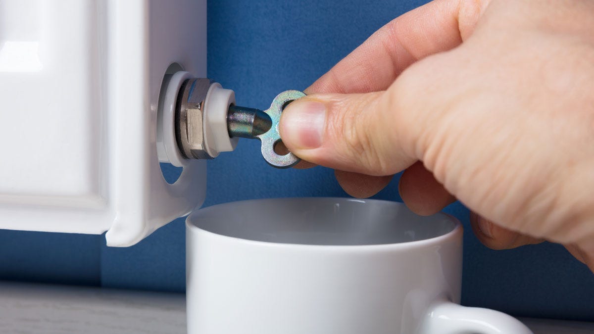 Bleeding a radiator with a bleed key and a cup to catch the water