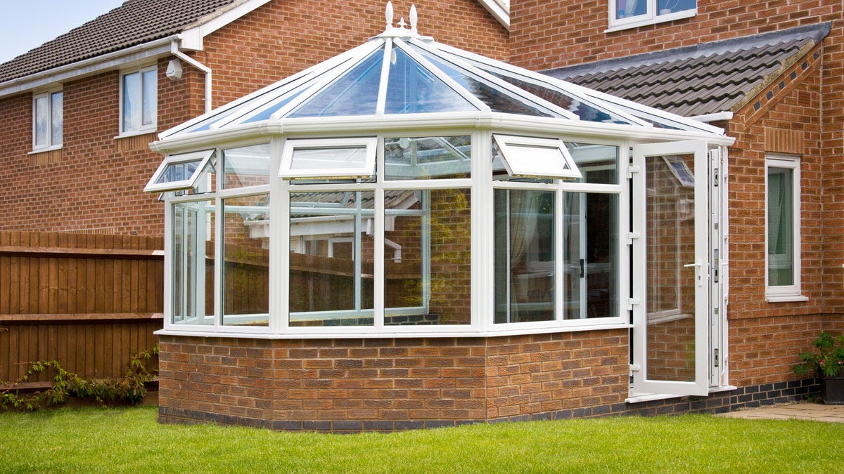 A brick and glazed conservatory with a glass roof