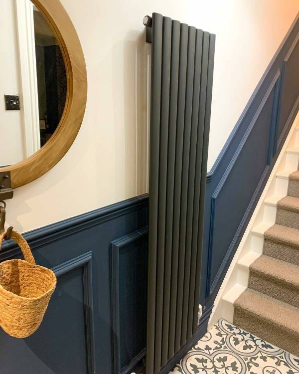 Anthracite vertical radiator by the stairs in a hallway