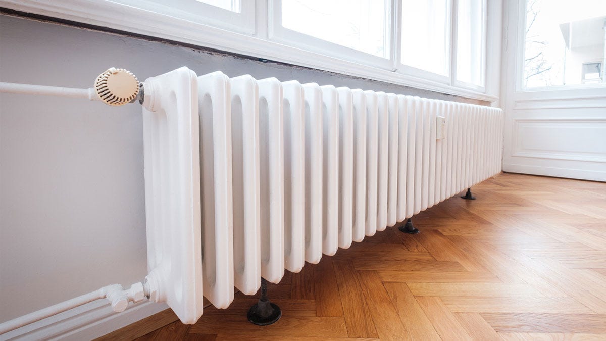 A low level white column radiator installed under a window
