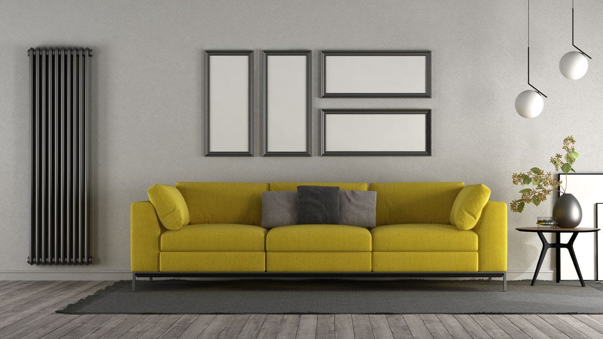 A vertical anthracite radiator in a contemporary living room next to a yellow sofa